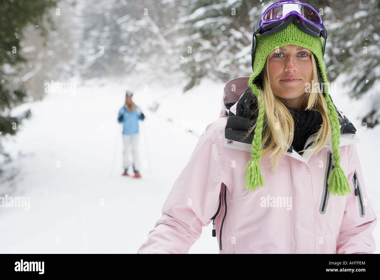 Smiling young woman on ski-slope, person in background, portrait Stock Photo