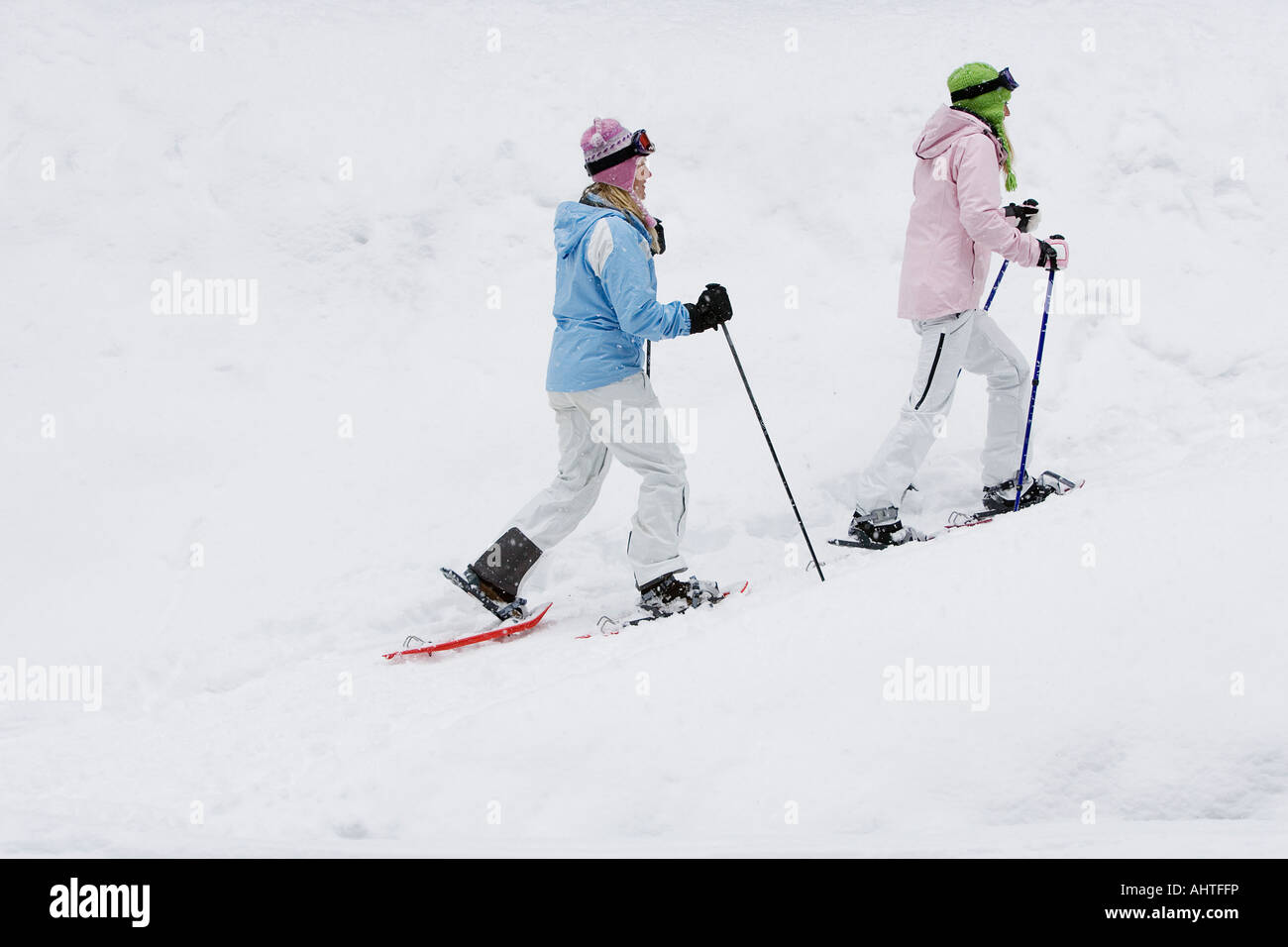 Side view of two young women woman walking in snow-shoes, side view Stock Photo