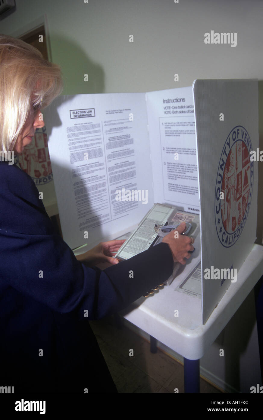 Woman voter in a voting booth selecting choices on a ballot CA Stock Photo