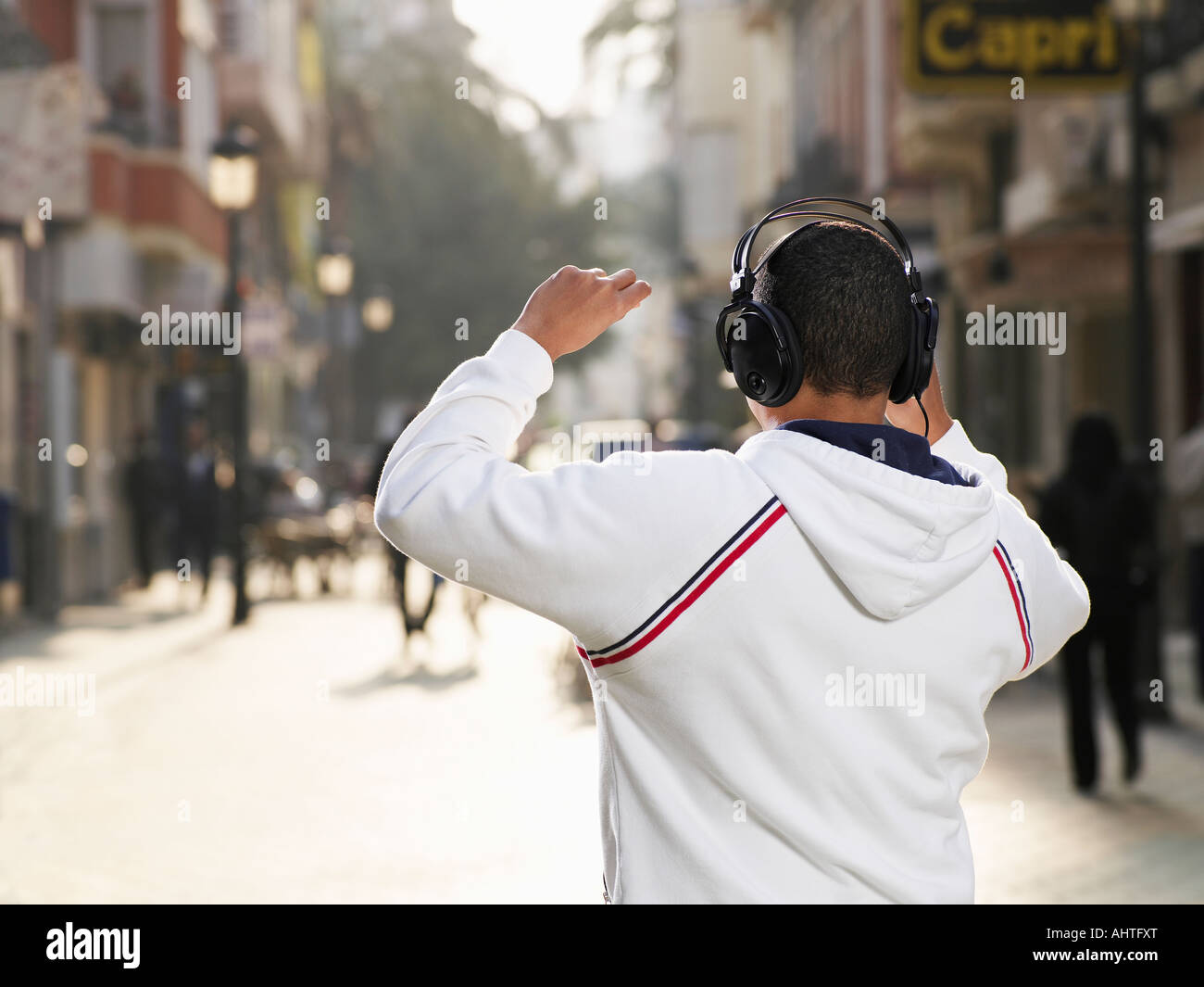 Young man standing in street wearing headphones, rear view Stock Photo