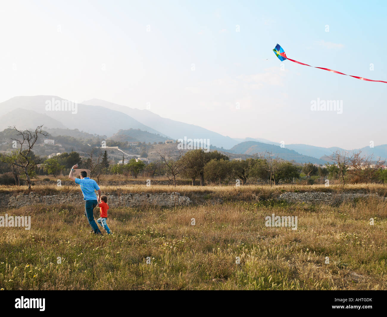 Father and son (4-6) running in a field with kite Stock Photo