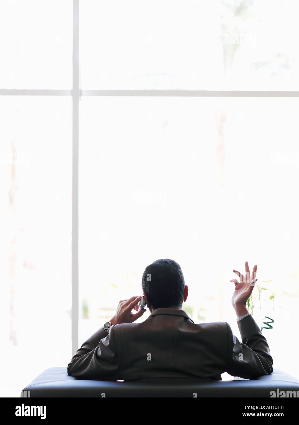 Businessman sitting in office using mobile phone, rear view Stock Photo ...