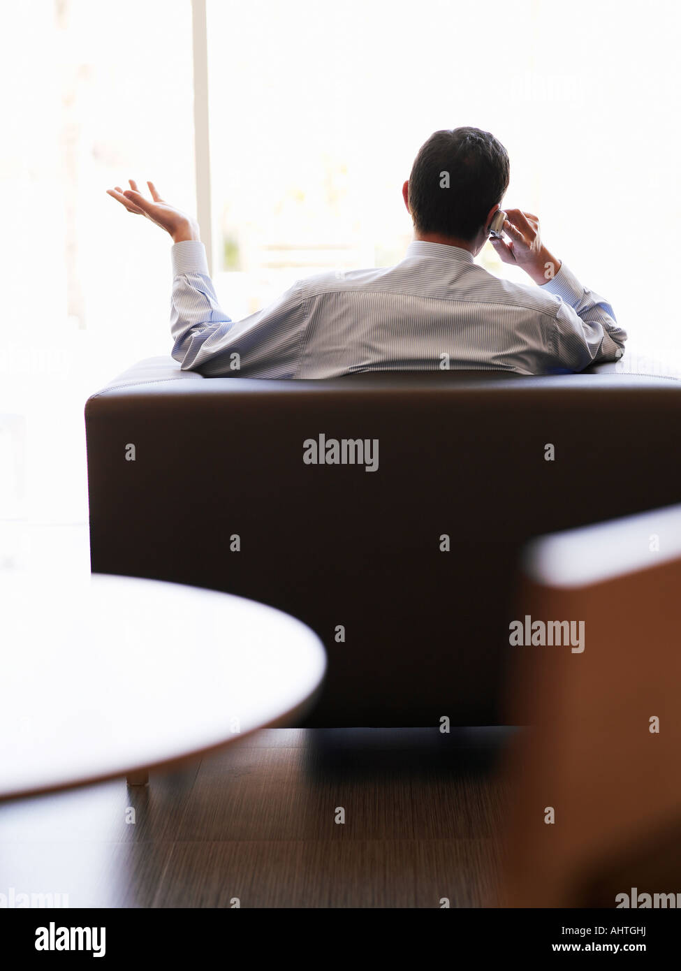 Businessman sitting in office using mobile phone, rear view Stock Photo ...