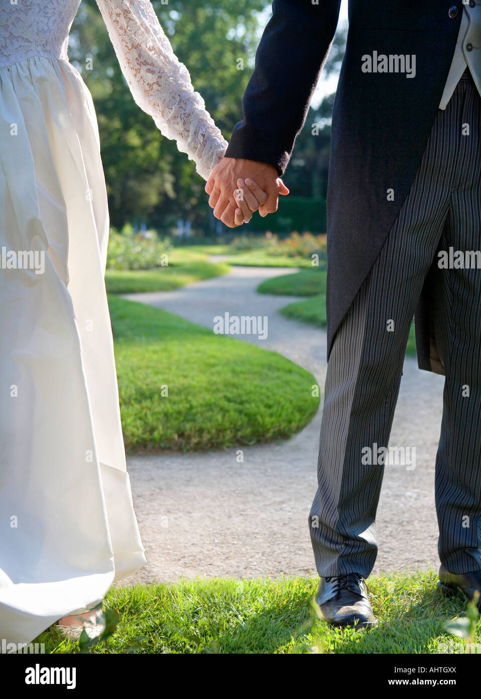 Bride and groom holding hands standing in garden hi-res stock ...