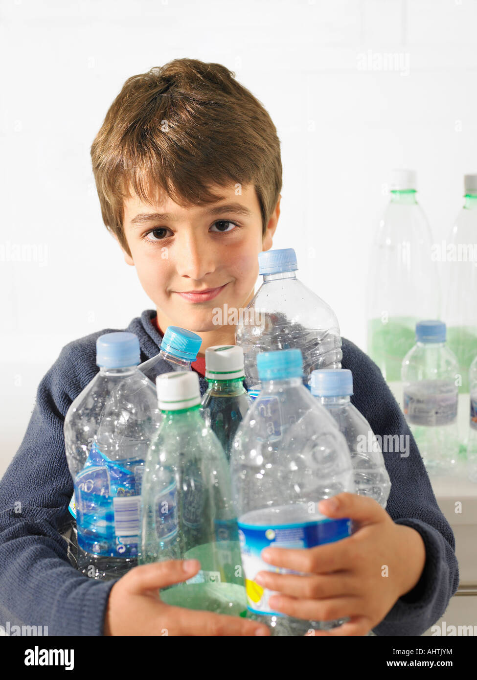 Young boy (6-8) holding an armful of recyclable plastic bottles