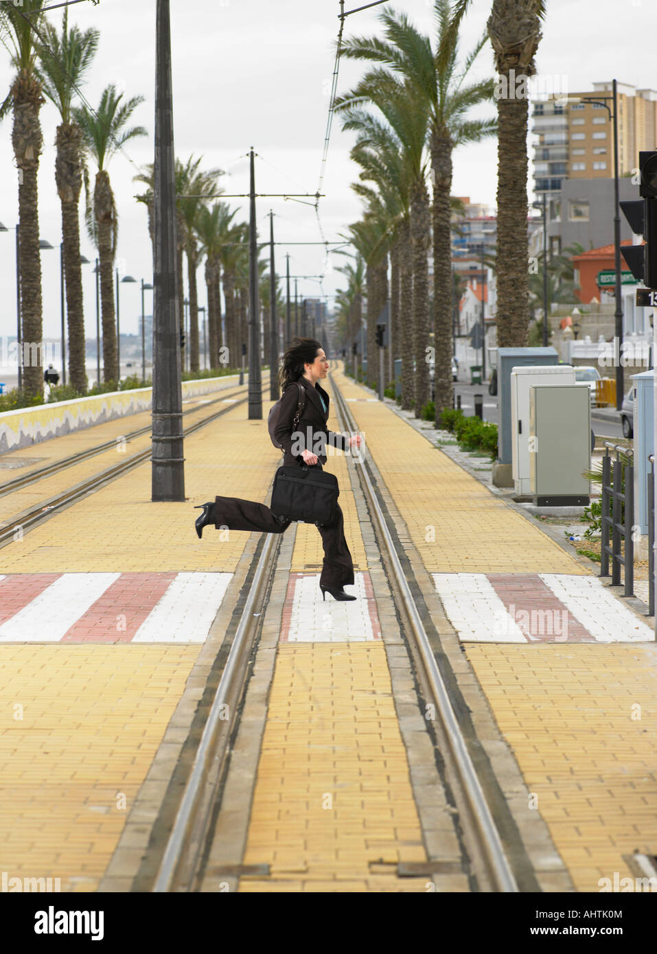 Businesswoman running across pedestrian crossing on tramway Stock Photo