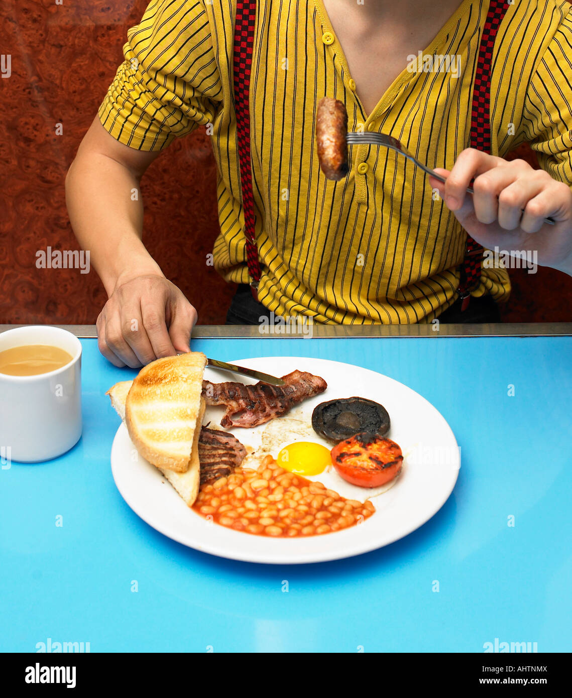 Young man eating fried breakfast in cafe, mid section Stock Photo