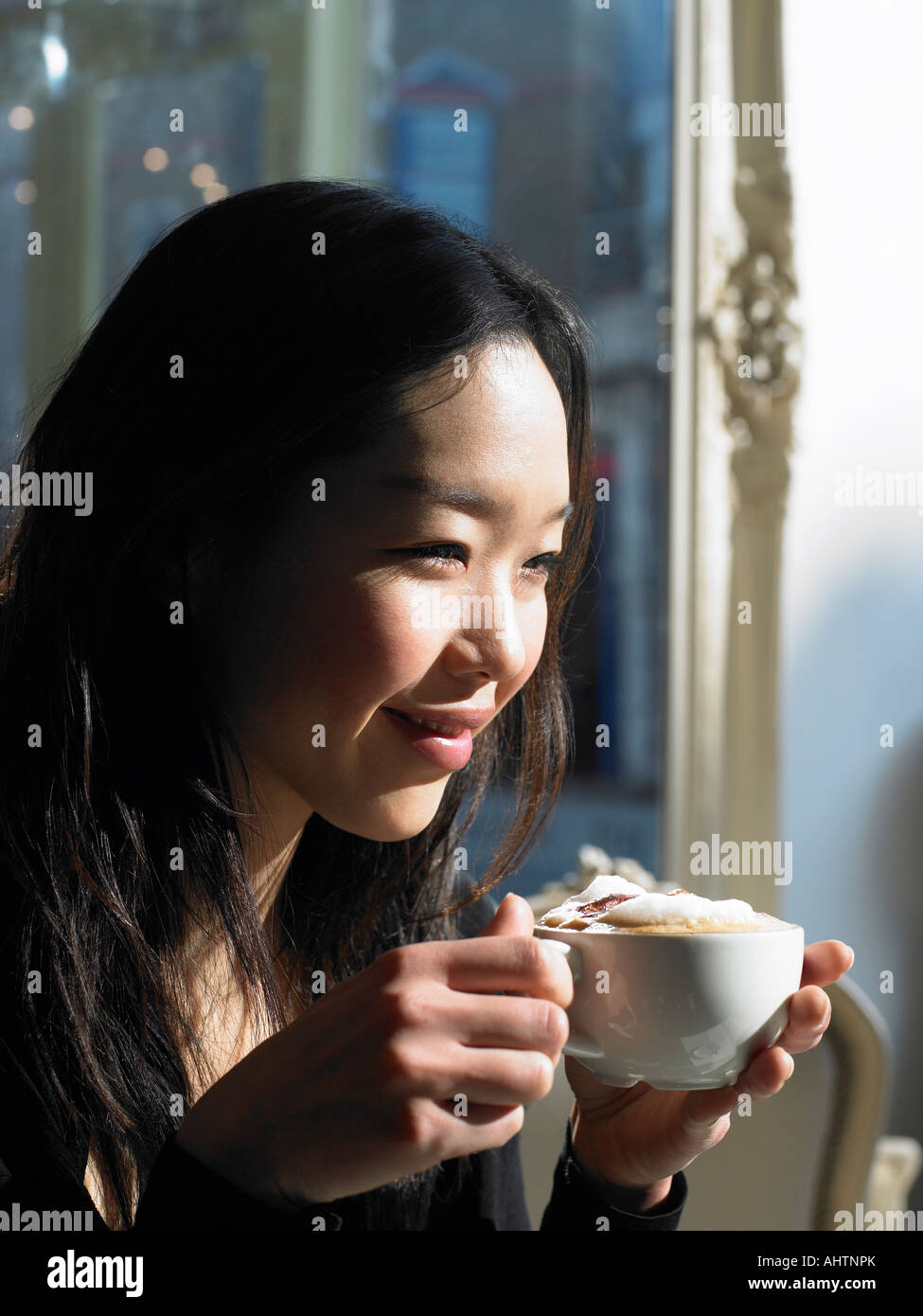 Young woman holding cappuccino, smiling, close-up Stock Photo