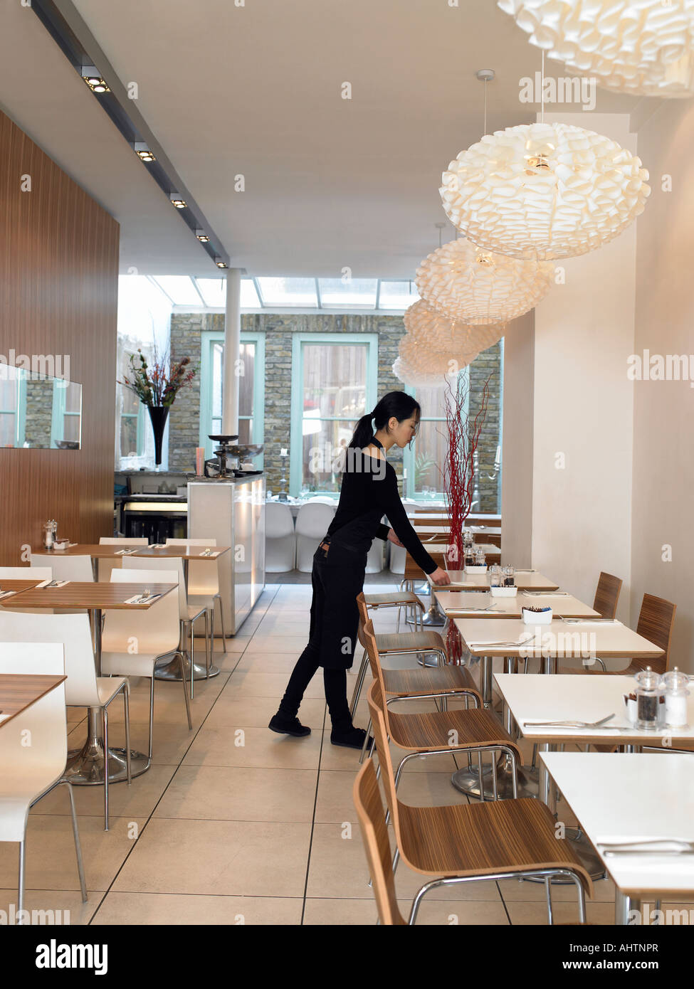 Young waitress setting tables in empty restaurant Stock Photo