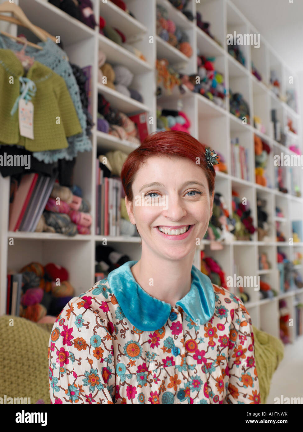Woman sitting in craft shop, smiling, portrait, close-up Stock Photo