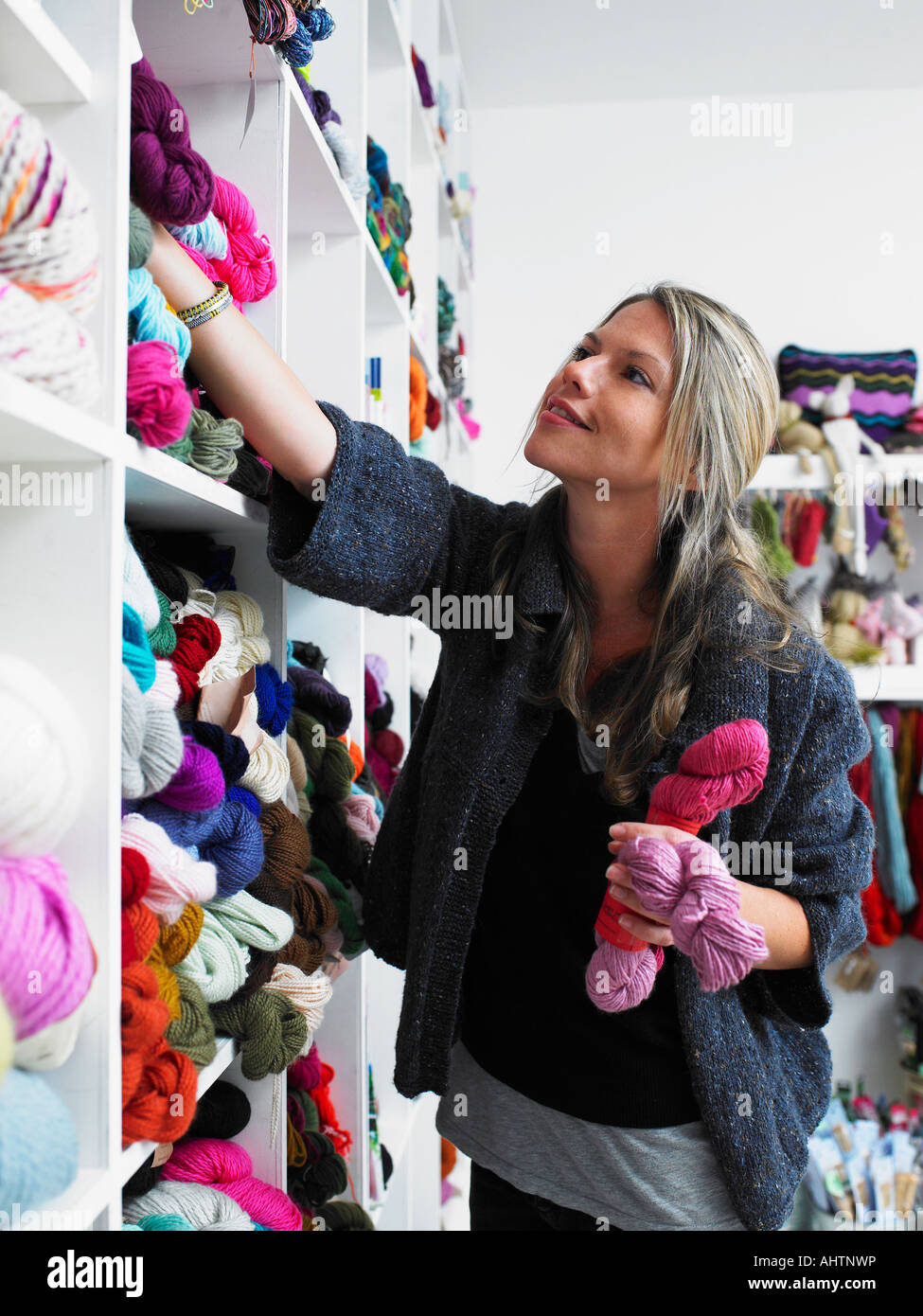 Young woman choosing wool in craft shop, smiling Stock Photo
