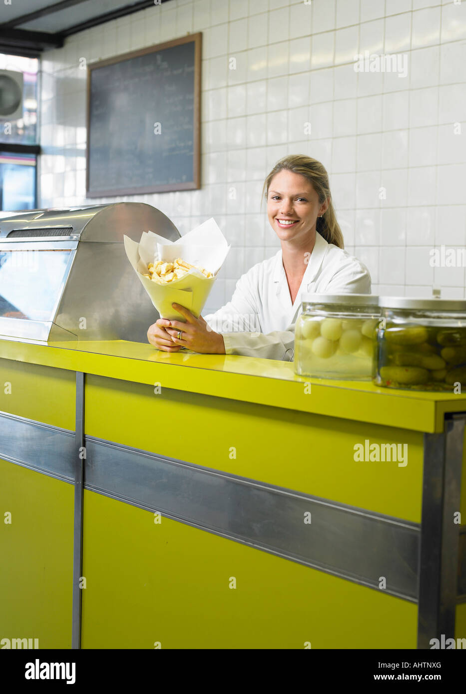 Young woman serving in fish and chip shop, smiling, portrait Stock Photo