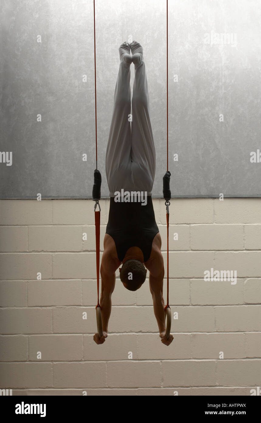 Male gymnast balancing upside down on rings, rear view Stock Photo