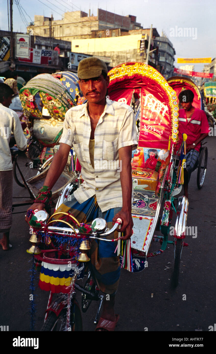 Colourful cycle rickshaw and driver on the busy streets of Dhaka. Bangladesh Stock Photo
