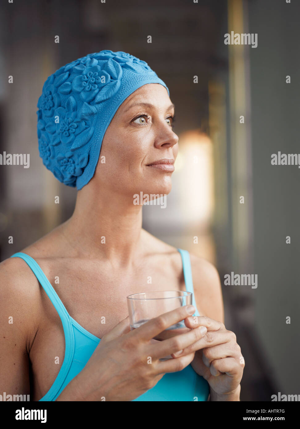 Mature woman wearing bathing suit, holding glass of water Stock Photo