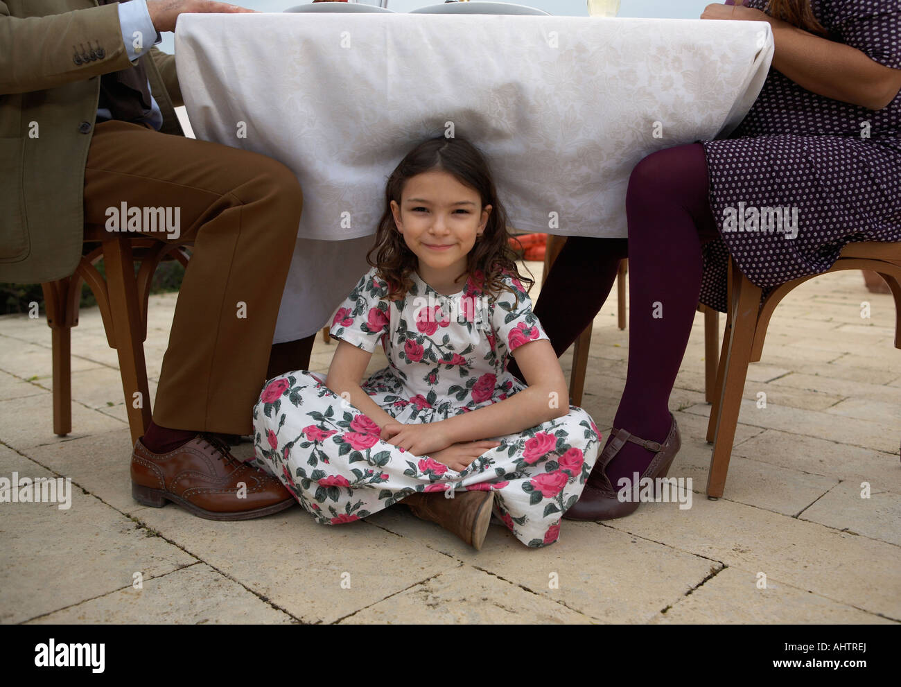 Girl (9-11) sitting under family table, portrait Stock Photo
