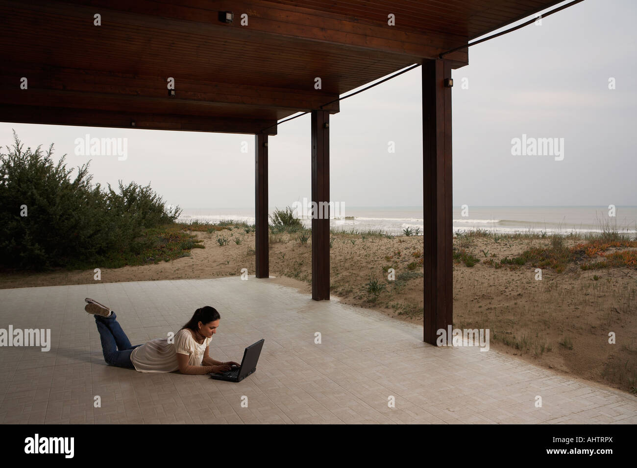 Young woman using laptop on beach patio Stock Photo