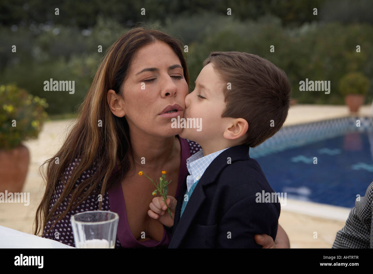 Mother kissing son (4-6) at the table, outdoors Stock Photo