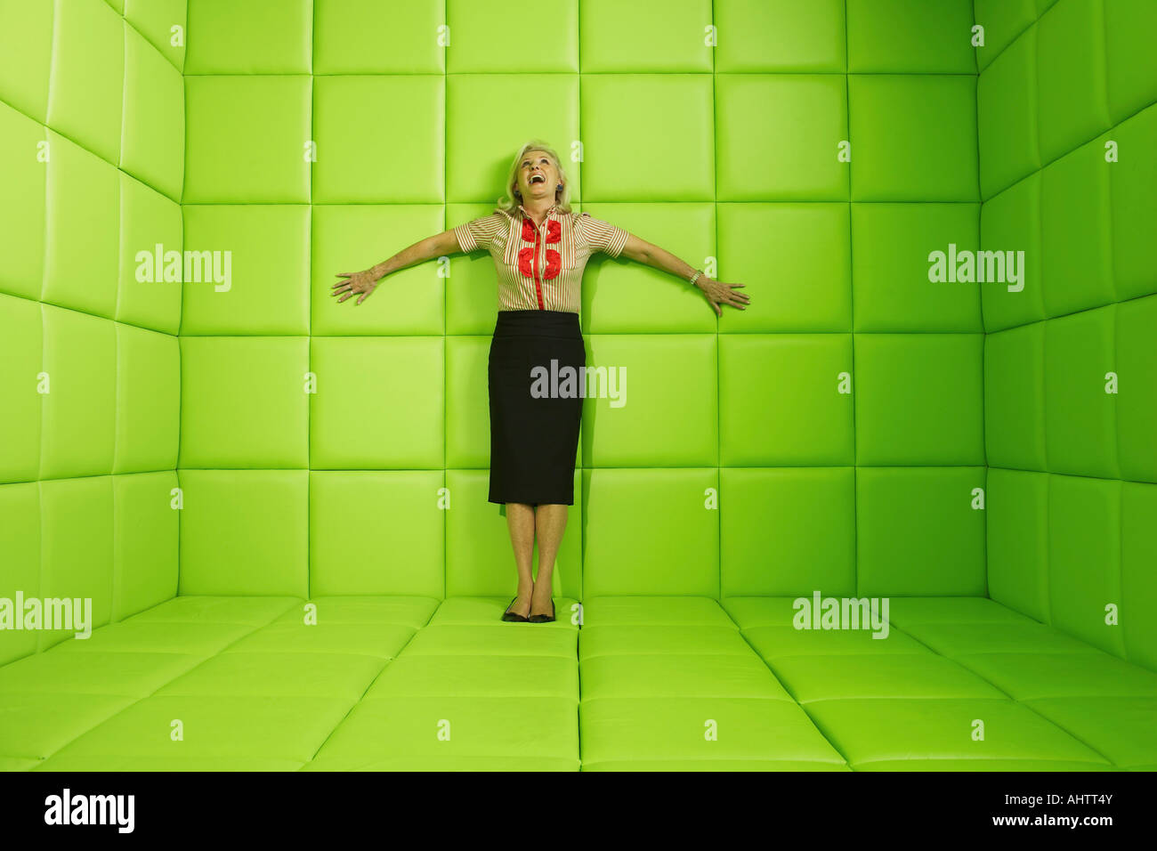 Woman laughing standing against wall of green padded cell Stock Photo