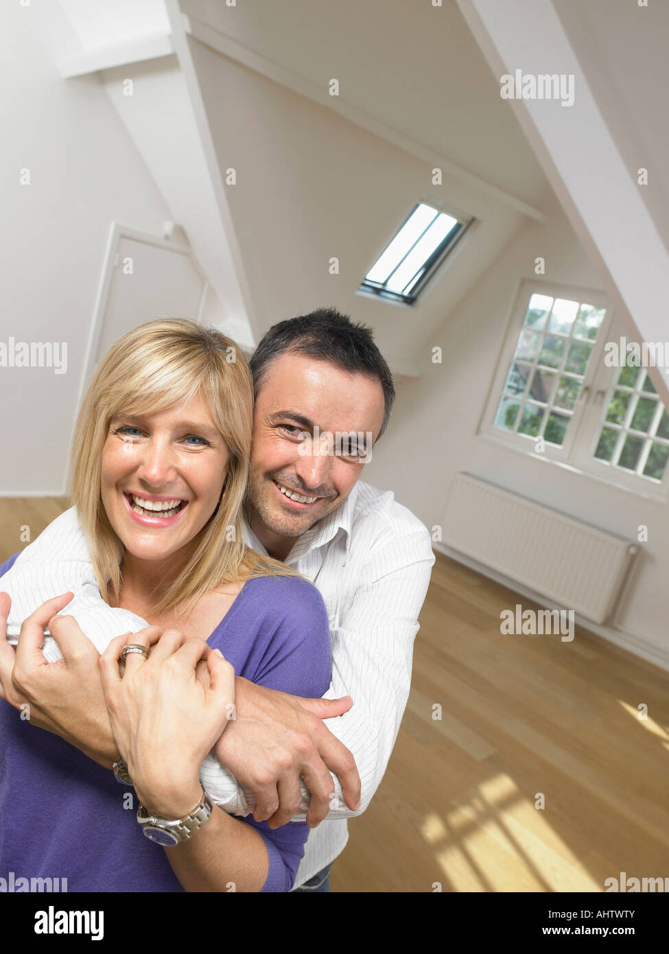Happy couple holding each other into white empty loft. Portrait. Stock Photo