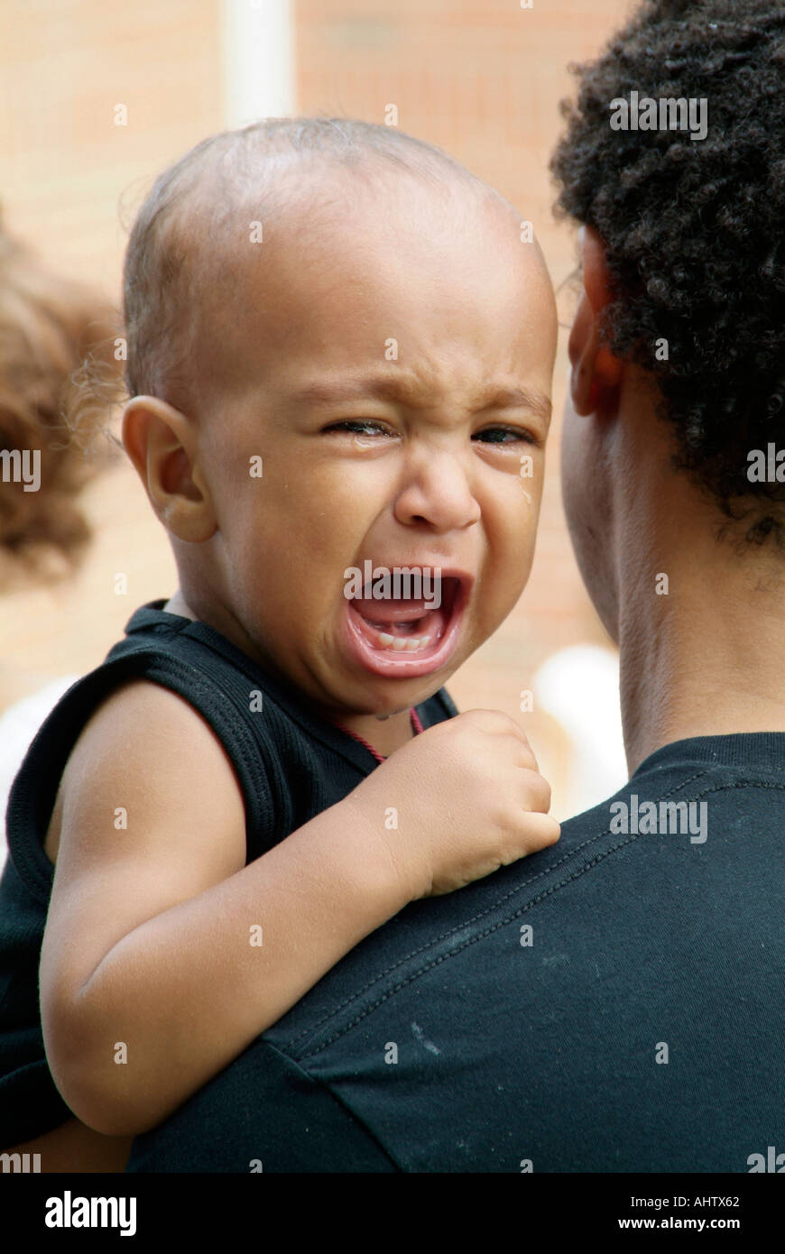 Child being held by father cries after throwing a temper tantrum Stock