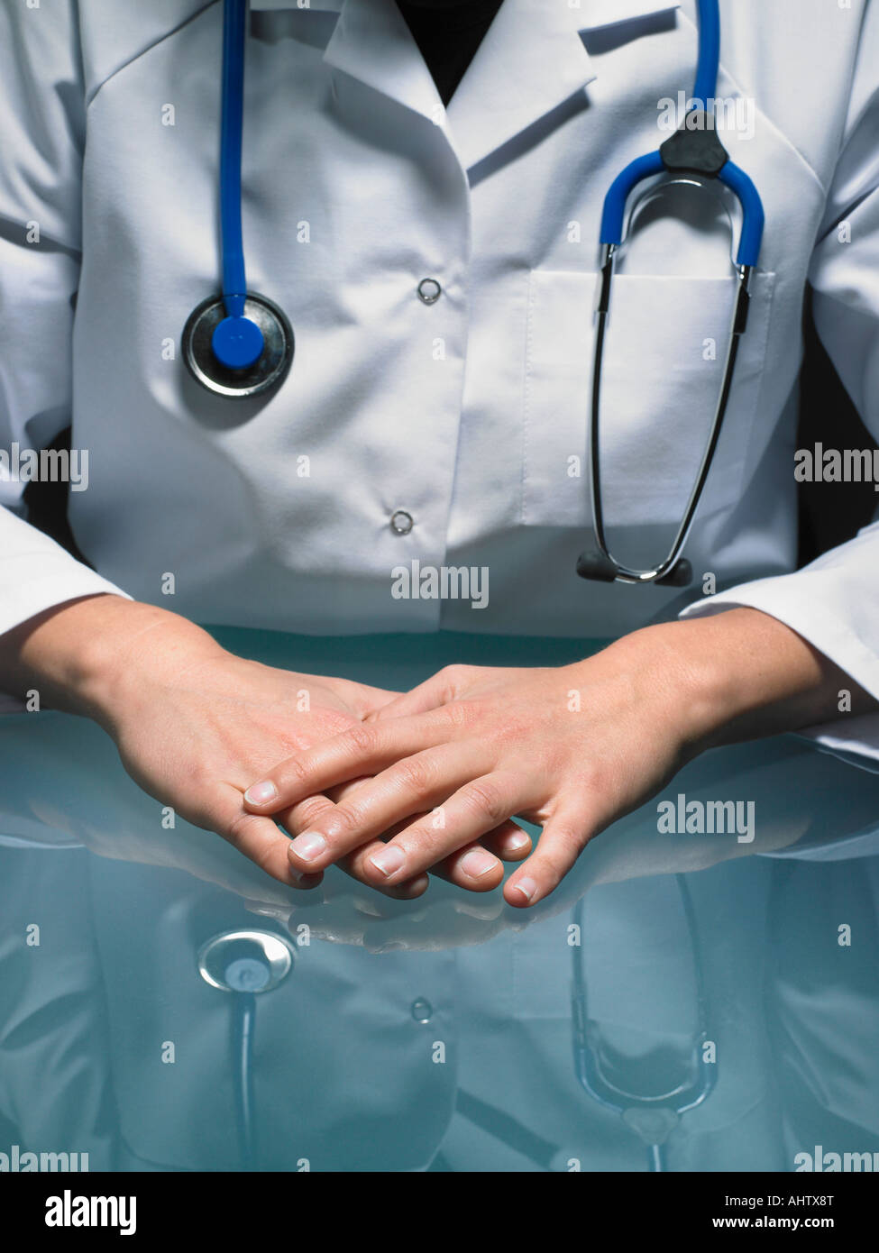 Close up of hands of female doctor at her desk carrying a stethoscope. Stock Photo