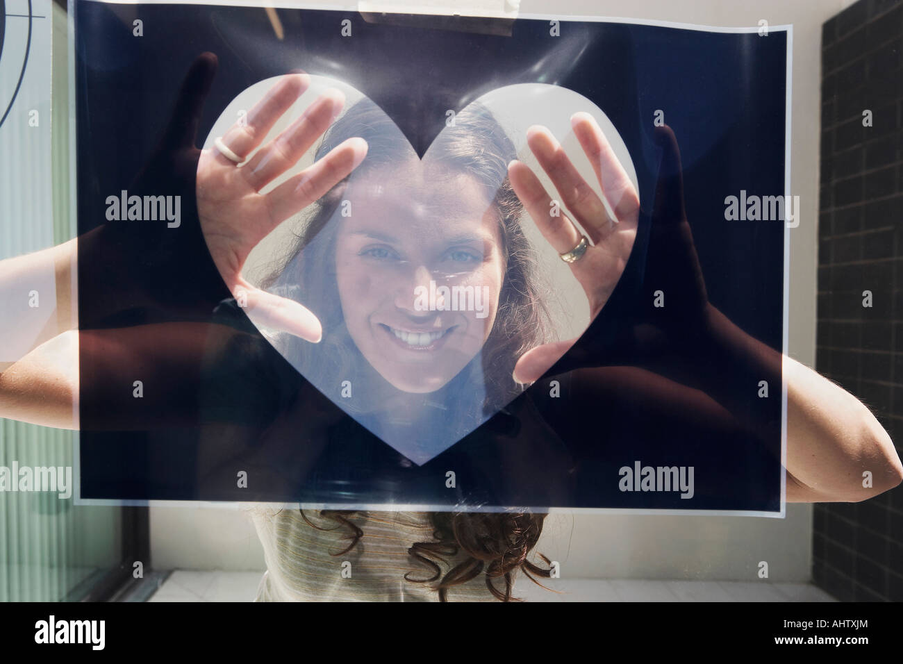 Young woman seen through heart shaped graphic. Stock Photo