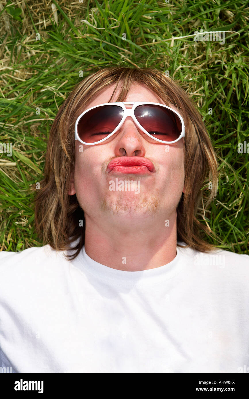 Male lying on grass wearing sunglasses pouting Stock Photo Alamy