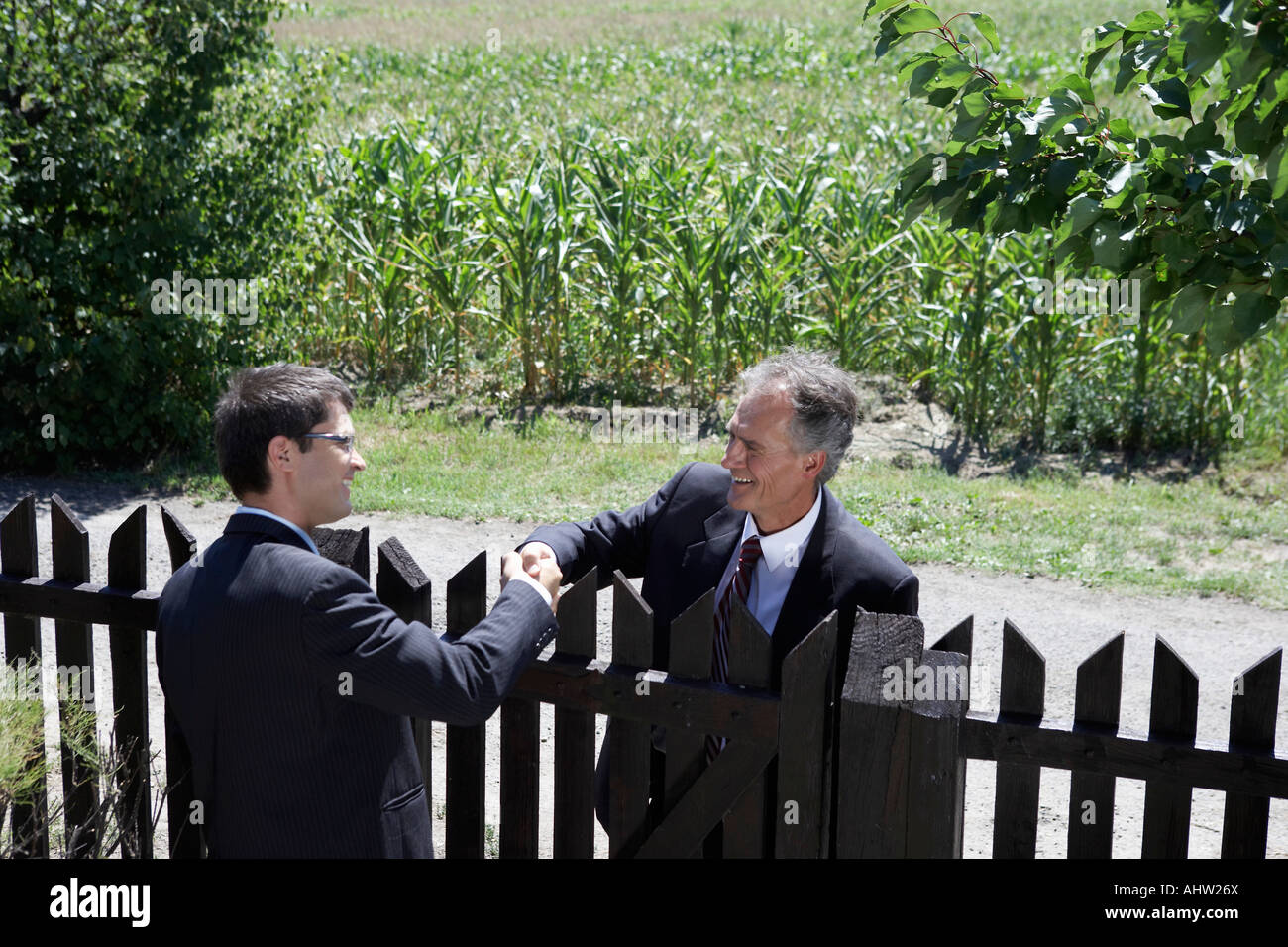 Businessmen greeting each other over wooden fence Stock Photo - Alamy