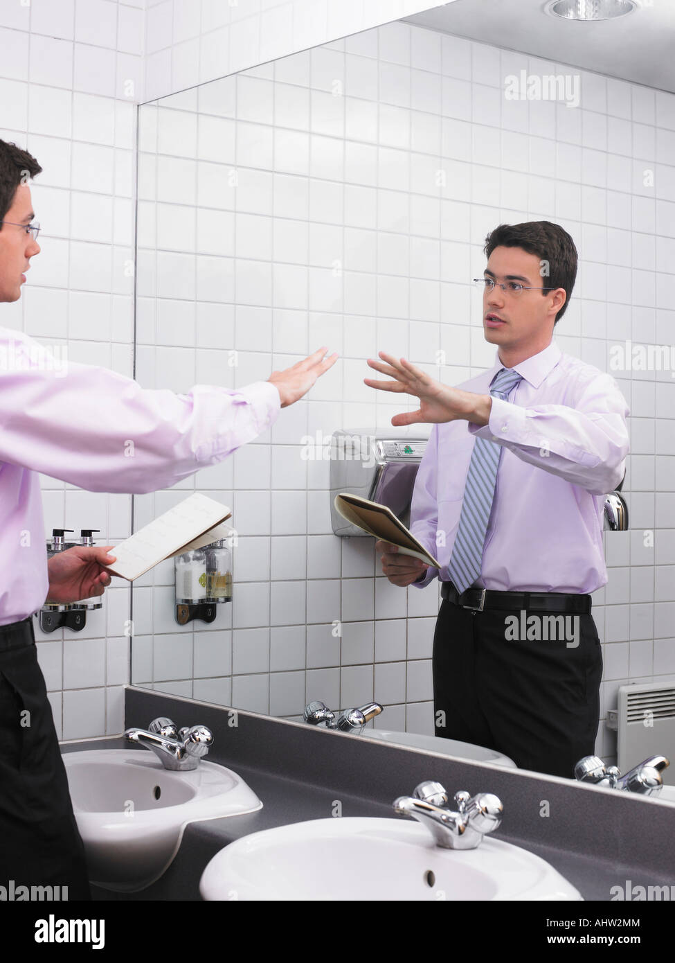 Man practicing speech in office washroom mirror Stock Photo Alamy