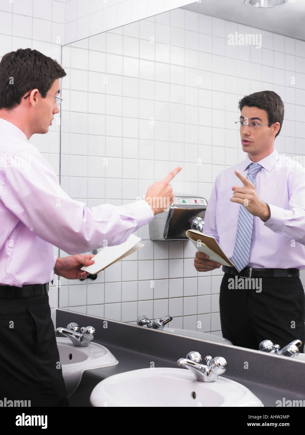 Man practicing speech in office washroom mirror Stock Photo Alamy