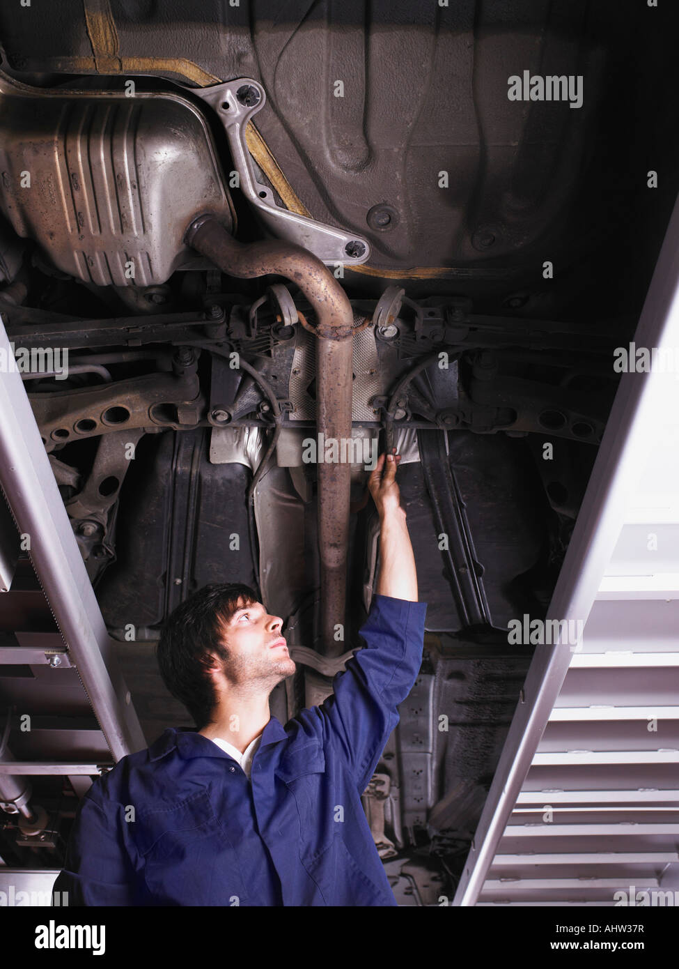 Mechanic standing under raised car Stock Photo Alamy