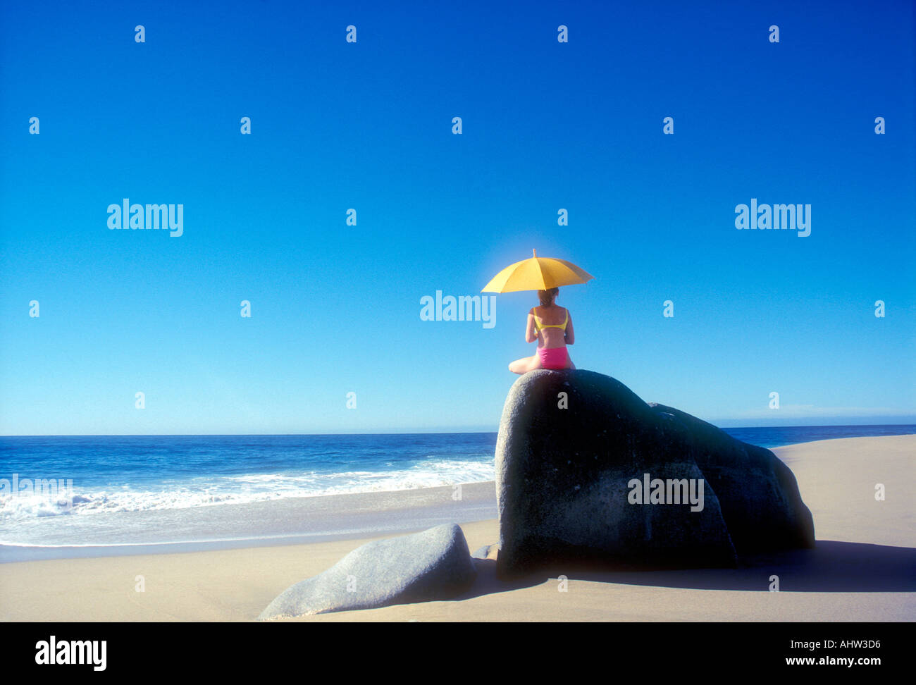 Woman sitting on rock with umbrella in Cabo san Lucas Baja California Mexico Model Released Photo Stock Photo