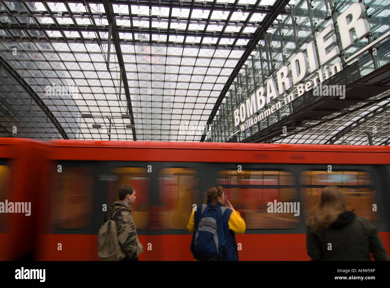 Horizontal view of several people waiting for a local S-Bahn train as it approaches the platform at Berlin Hauptbahnhof station. Stock Photo