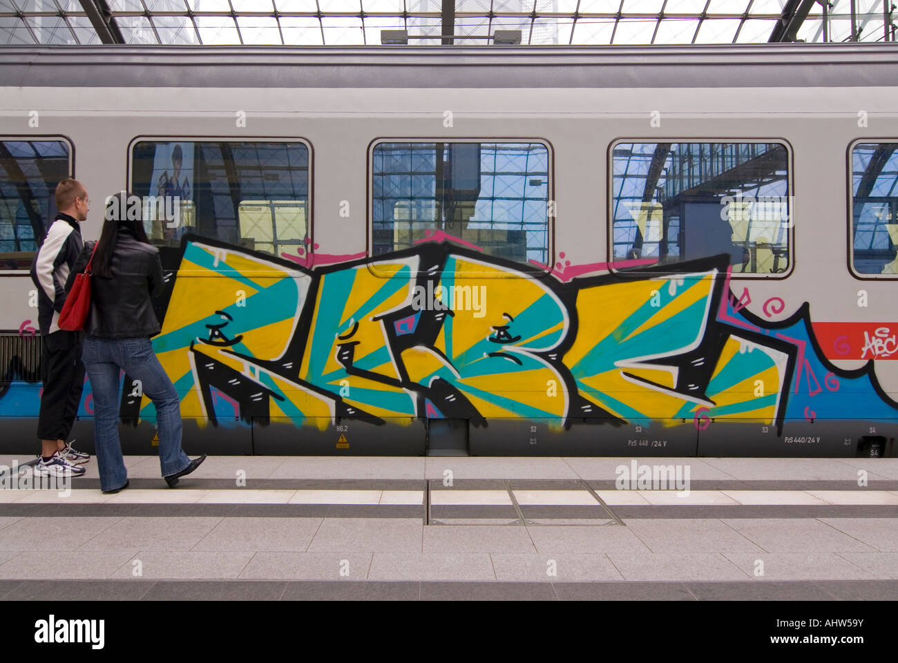 Horizontal close up of an InterCity train carriage covered in graffiti waiting on a platform at Berlin Hauptbahnhof. Stock Photo