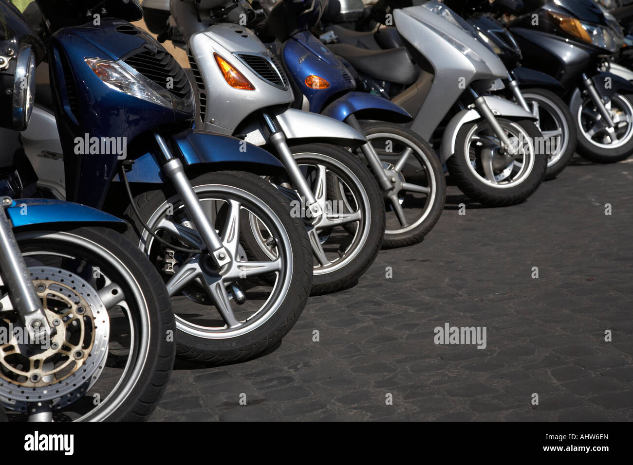 Row of front wheels of scooters parked on a street in Rome Lazio Italy