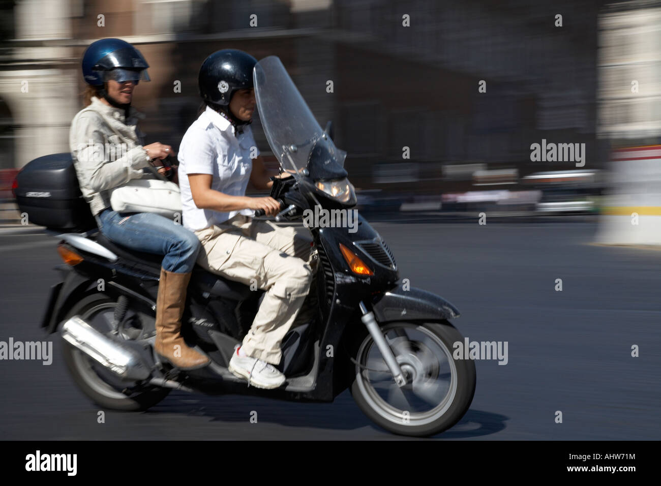 Scooter driver with female pillion passenger speeds past through Piazza