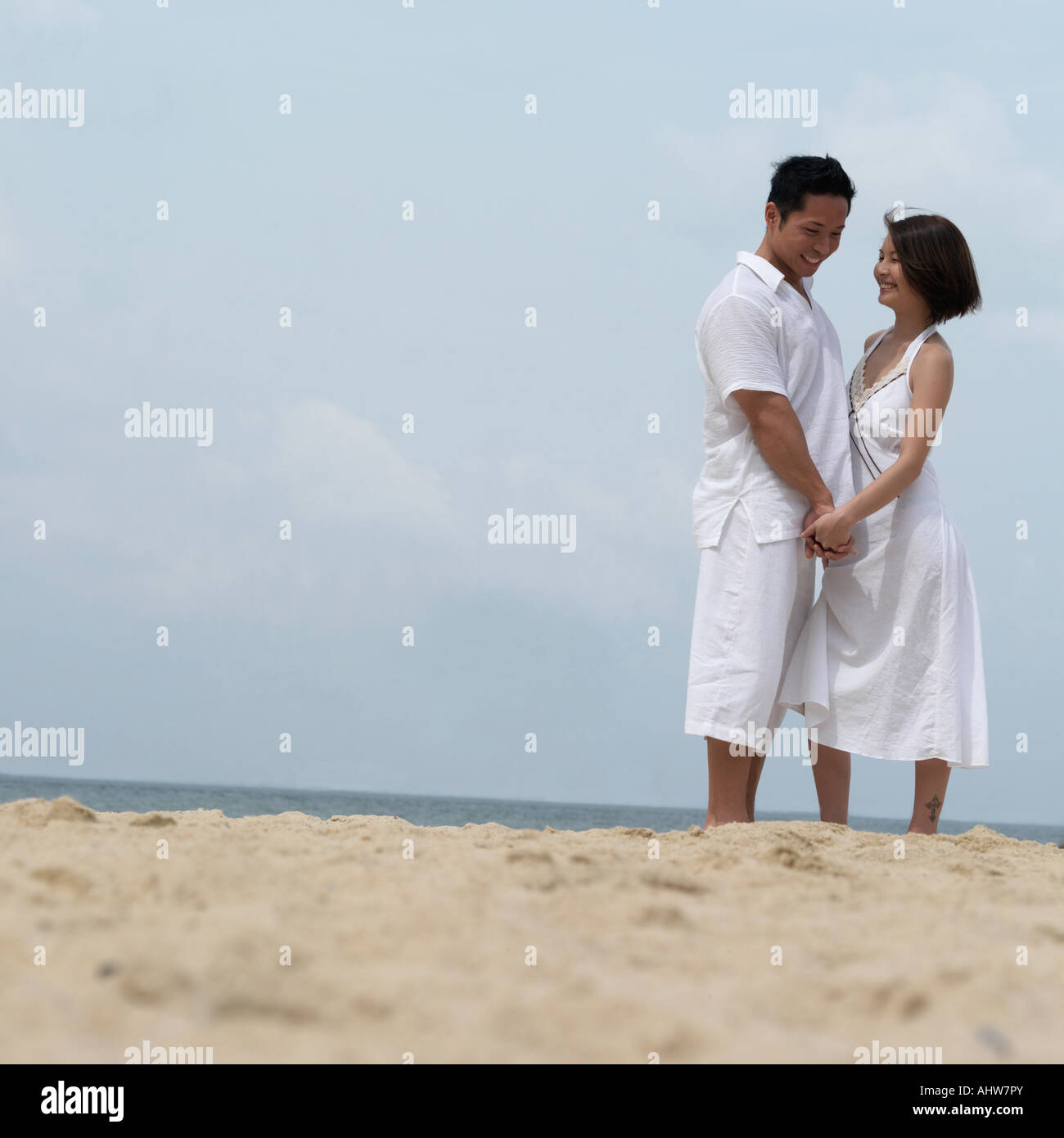 Couple standing by the beach, holding hands Stock Photo - Alamy