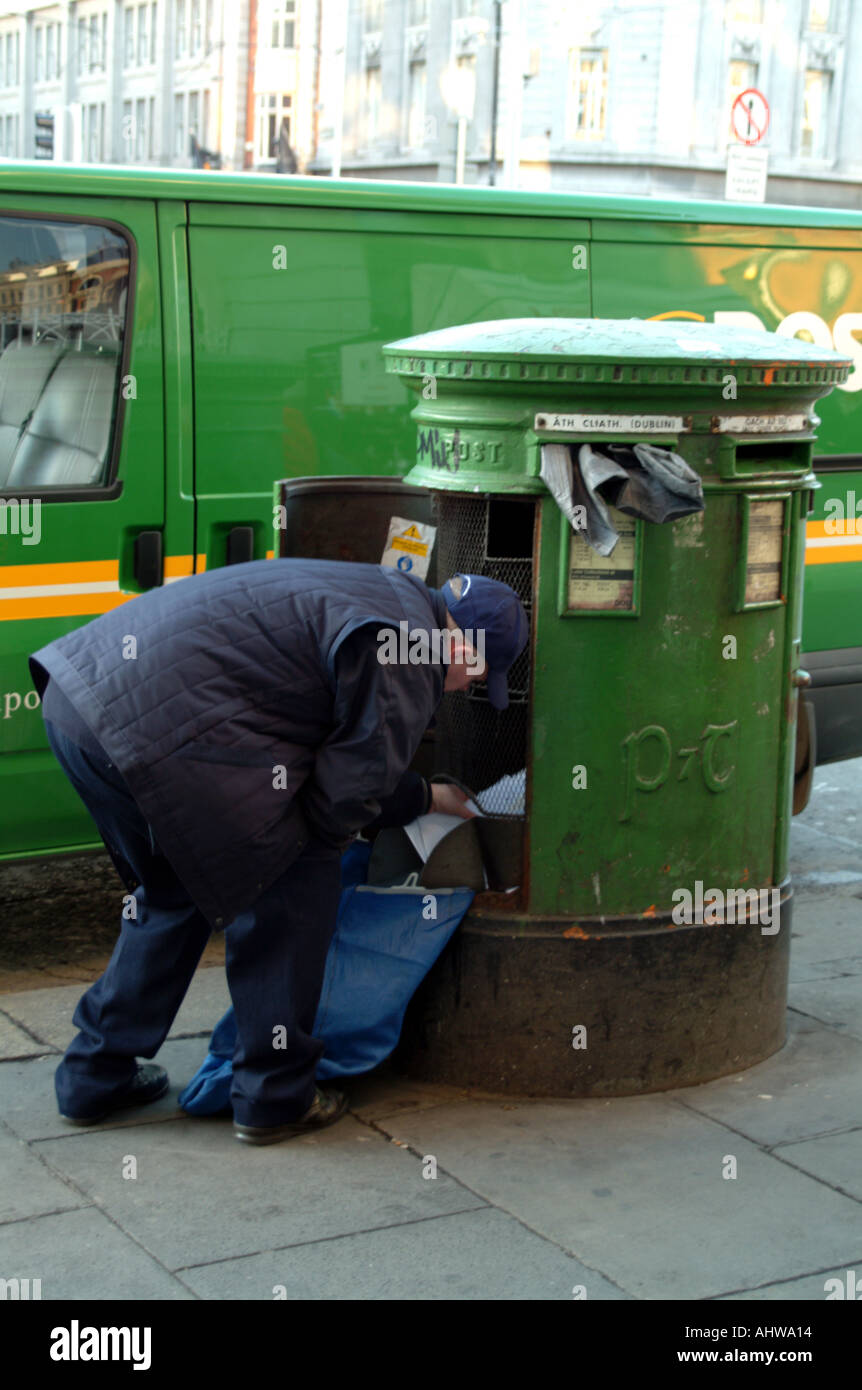 Postman empties green double letter box in Dublin city centre Ireland EU Stock Photo