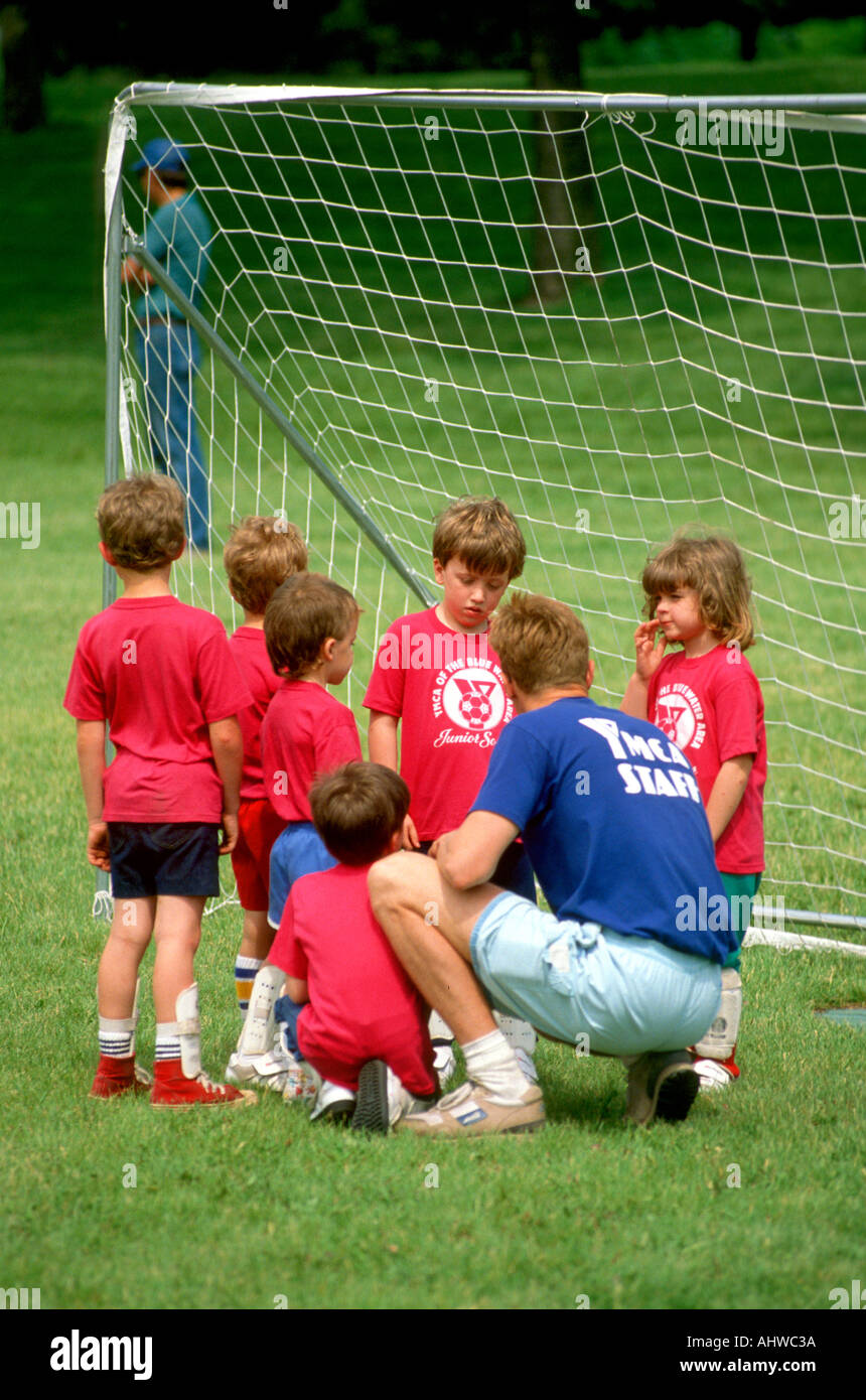 Coach with 5 6 year old co ed soccer team giving instructions to boys and girls Stock Photo