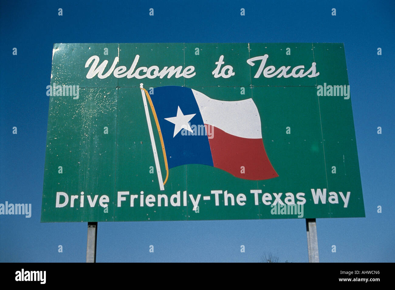 This is a road sign that says Welcome to Texas drive friendly the Texas way It is against a blue sky with he Texas state flag Stock Photo