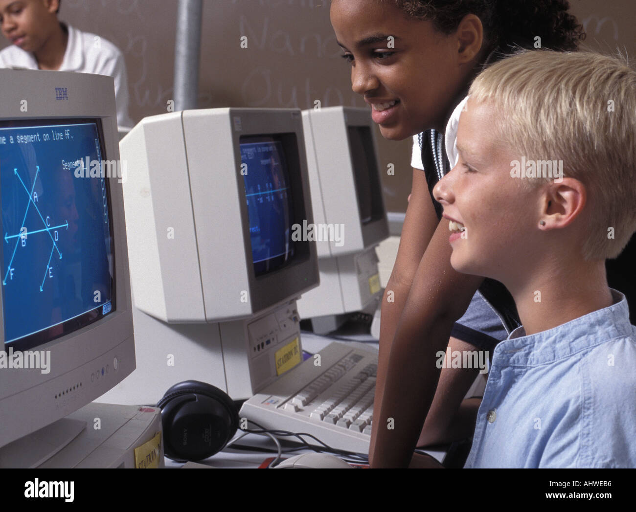 Caucasian and African American students using computer in middle school class Stock Photo