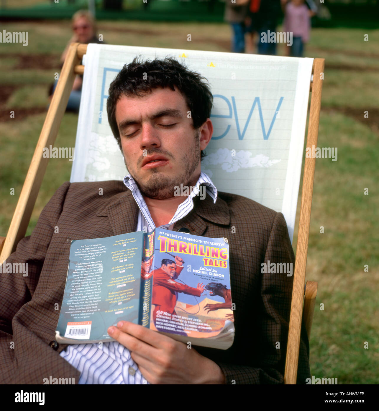 A young man fallen asleep in a deckchair while reading Thrilling Tales book at the Hay Festival Hay on Wye Powys Wales  UK KATHY DEWITT Stock Photo