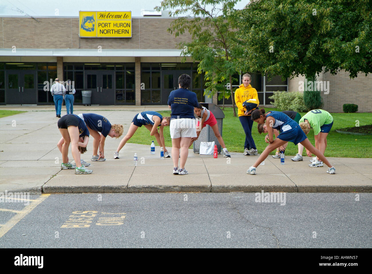 High school girls cross country running team stretches their muscles