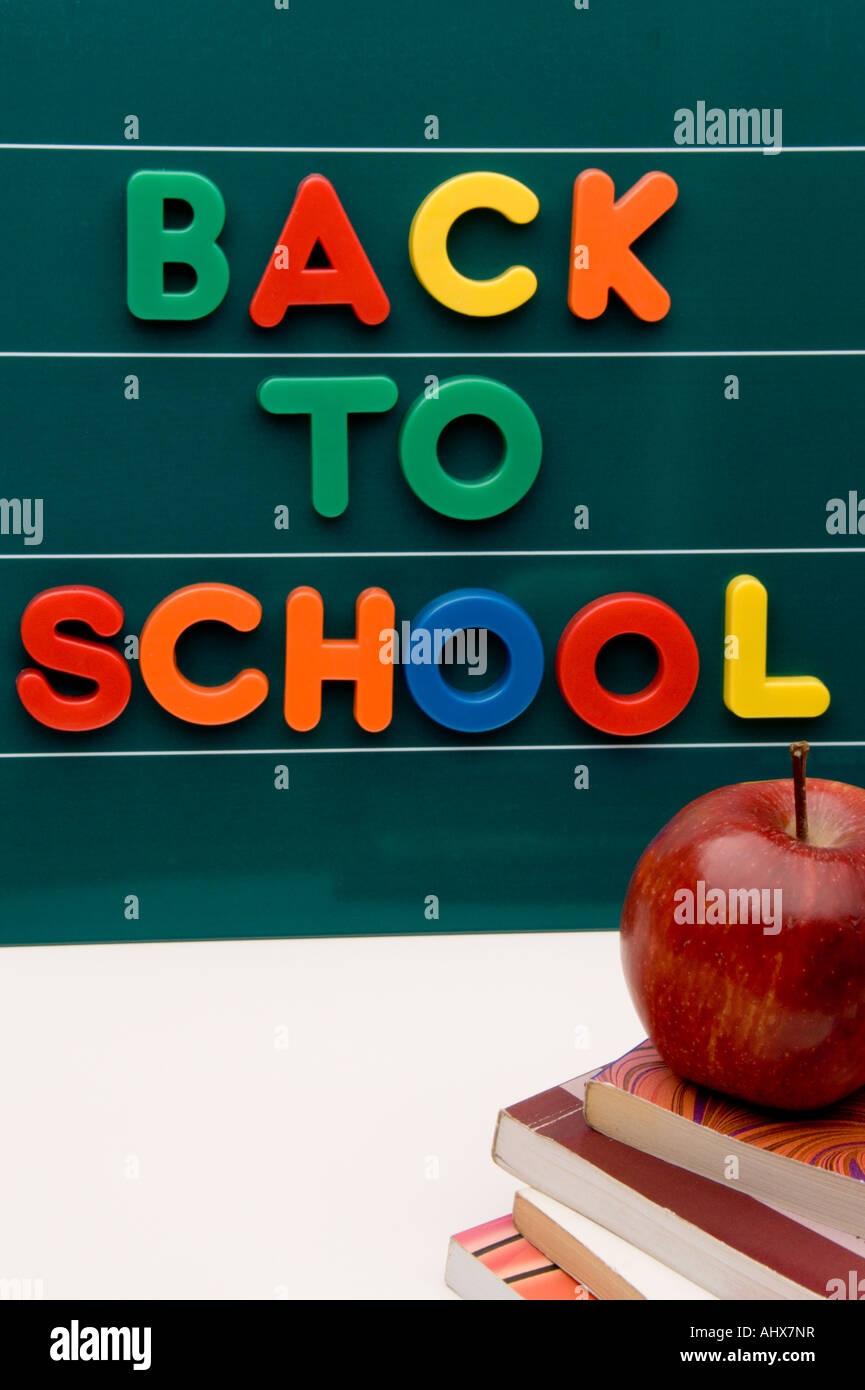 Blackboard with letters and books with apple, displaying the phrase back to school. Stock Photo