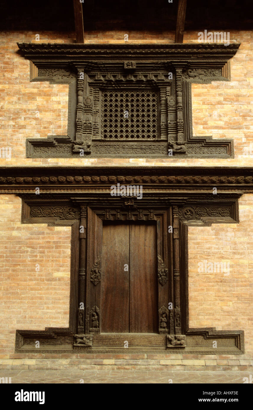 Intricately carved wooden door and window in Newari style, Kathmandu Valley, Nepal. Traditional architecture on a brick wall. Stock Photo