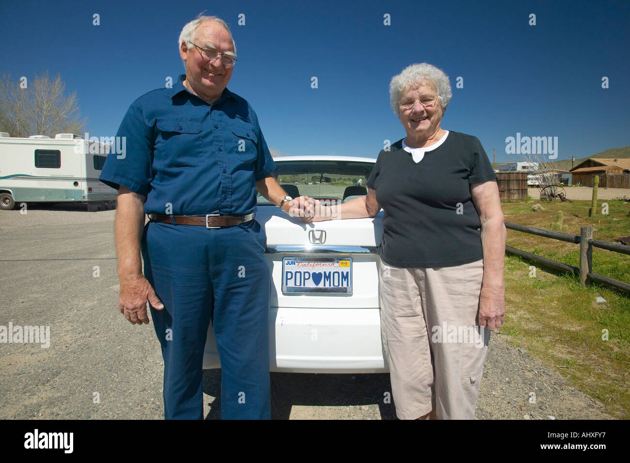 Elderly couple pose with California license plate that reads Pop loves Mom Stock Photo