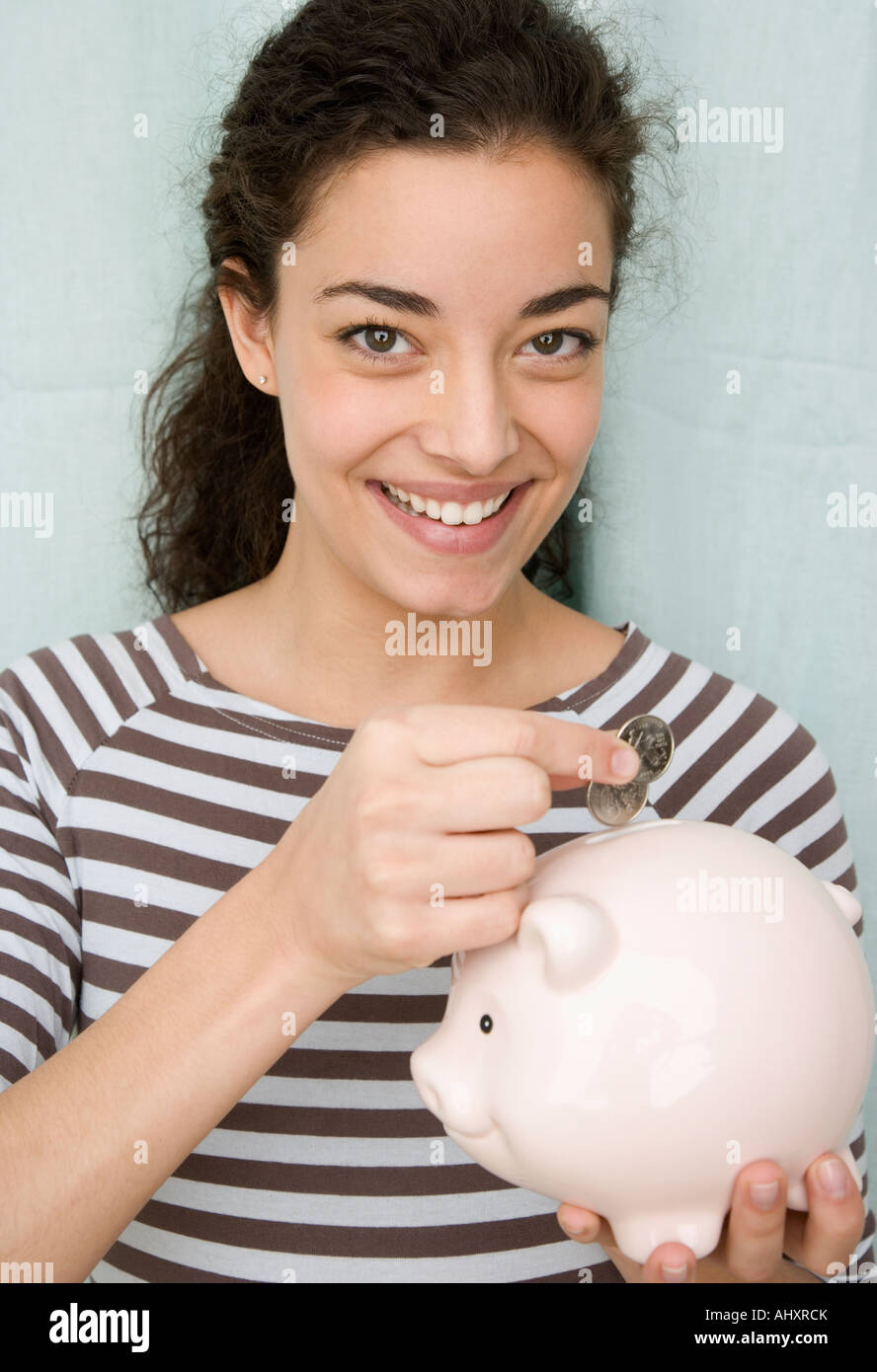 Woman putting coins in piggy bank Stock Photo