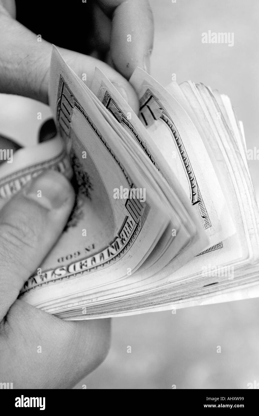 black and white image of details of hand and fingers of man counting bundle of one hundred american dollars currency Stock Photo