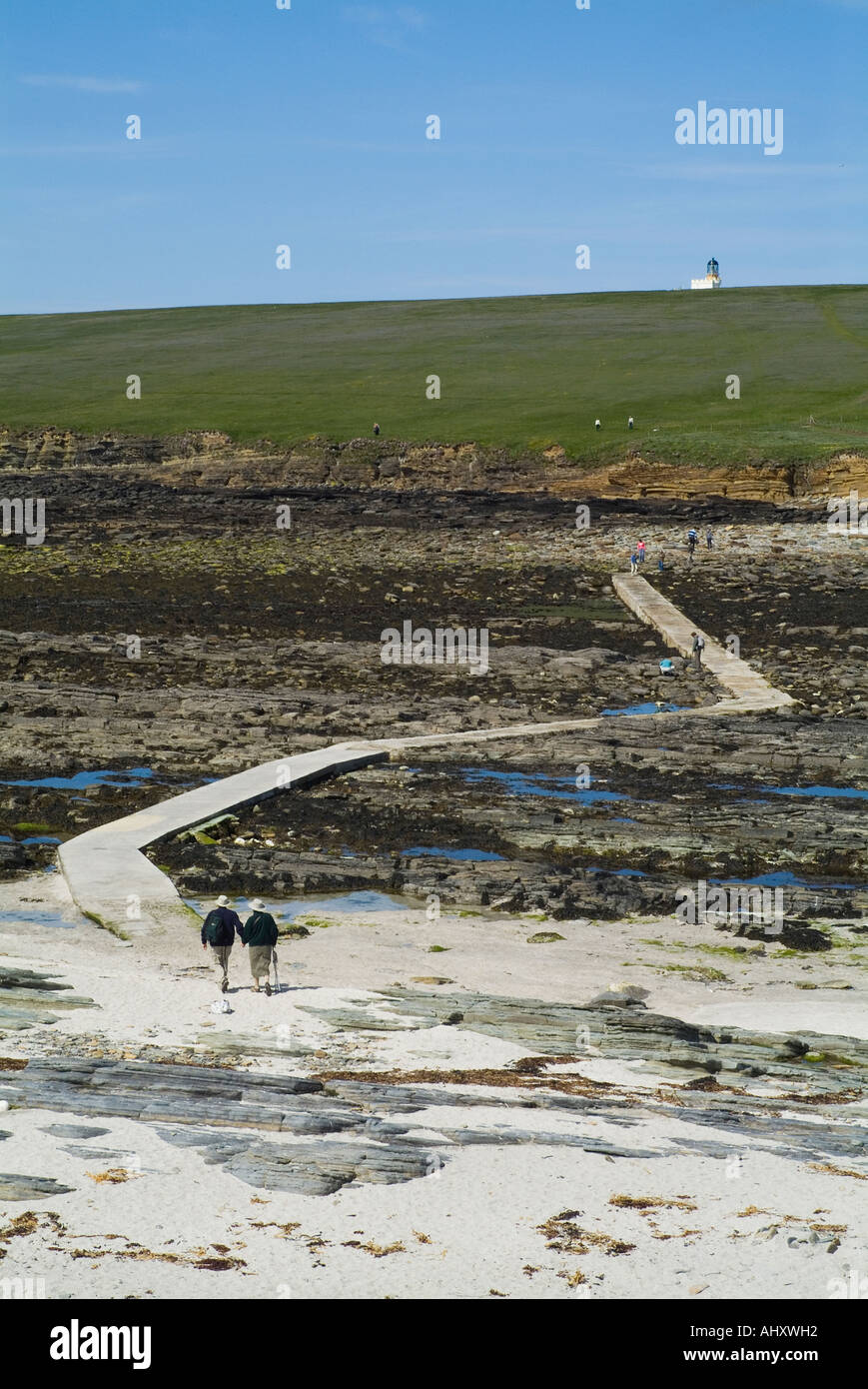 dh Causeway to lighthouse island BROUGH OF BIRSAY ORKNEY SCOTLAND Couple walking over tourist holiday uk islands hiking walkers summer hikers Stock Photo